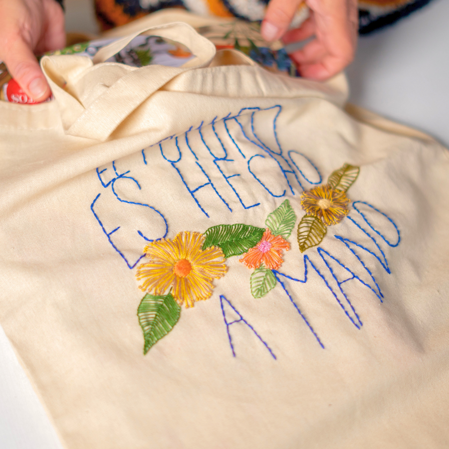 Totebag con la frase «El futuro es hecho a mano» bordada en azul, con flores de colores